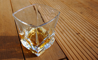 glass glass with whiskey, outside on a wooden textured surface, on a Sunny day
