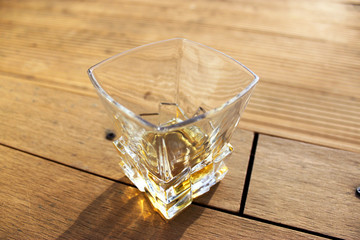 glass glass with whiskey, outside on a wooden textured surface, on a Sunny day
