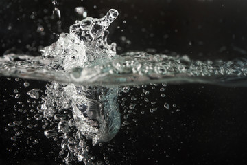 Water splashing as it's poured into aquarium tank, black background
