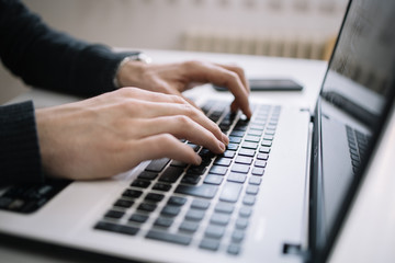 Male's hands typing on a laptop keyboard