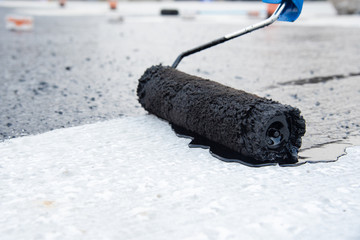 Worker applies bitumen mastic on the foundation