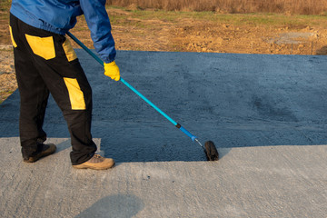 Worker applies bitumen mastic on the foundation