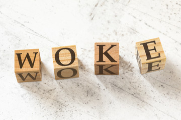 Four wooden cubes with letters WOKE meaning Wisdom, Opportunity, Knowledge and Empowerment on white working board.