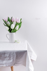 Bunch ofwhite and pink tulips in a white vase on white table
