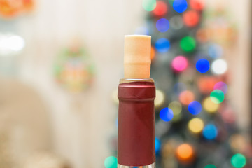 open wine bottle with blank bottle, festive background, glasses, candles, xmas tree with lights