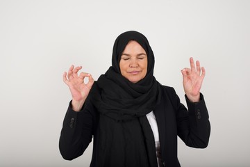 Meditation, religion and spiritual practices. Beautiful young blond haired female doing yoga in the morning outdoors after waking up, keeping eyes closed, holding fingers in mudra gesture.