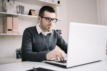 Male employee working on laptop at office desk