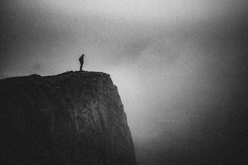 Minimal black texture background with girl standing on a cliff in fog