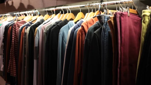 Men clothing shop, casual clothes on hangers and shelves in apparel store 