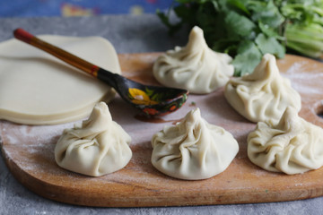 georgian dumplings khinkali with meat fillimg, cilantro, coriander on kitchen board close up photo with human hand