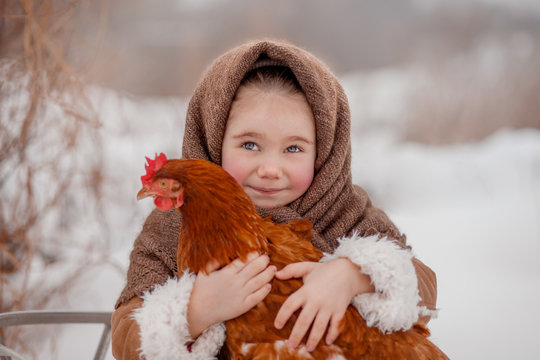 Cute little girl holding a red chicken