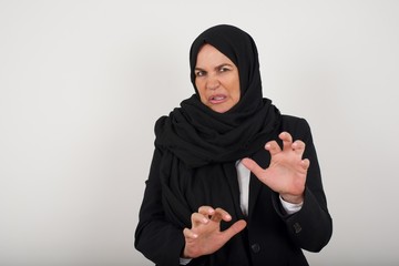 Ugh how disgusting! Displeased muslim woman dressed casual, says fie and has dissatisfied facial expression as sees something abominable or detestable, isolated over  background.