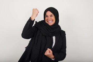 Beautiful muslim woman being happy and excited expressing winning gesture. Successful and celebrating victory, triumphant.