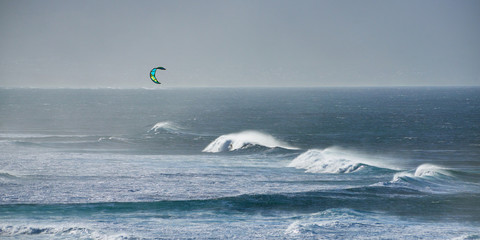 Panoramic view of the ocean waves with kite surfer on a windy day on Maui island in Hawaii.
