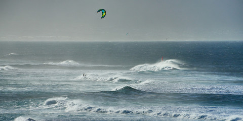 Panoramic view of the ocean waves with kite surfer on a windy day on Maui island in Hawaii.