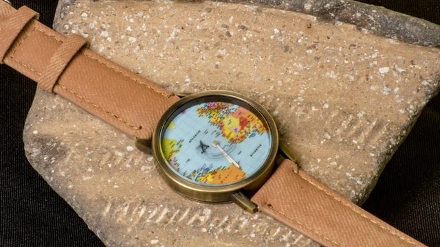 Time lapse de reloj de esfera mapamundi sobre pieza de barro antigua y fondo negro