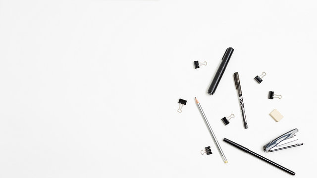 pen, marker, stapler, eraser, bunch of black binder paper clips for documents, pencils, randomly scattered on white background. stationery isolated flat lay. top view of office equipment. copyspace