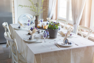 Easter festive spring table setting decoration, bunny ears shaped napkins, dyed eggs, cakes,...