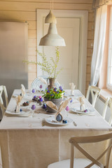 Easter festive spring table setting decoration, bunny ears shaped napkins, dyed eggs, cakes, flowers, selective focus