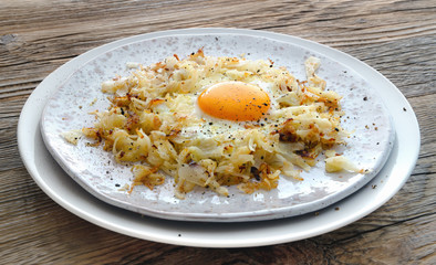 egg and fried cabbage on fleck ceramic plate on wooden background