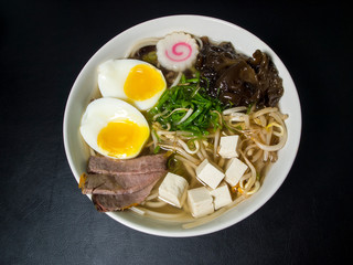Fototapeta na wymiar Ramen: Asian noodle soup with beef, eggs, fungi, vegetables, seaweed and naruto in a bowl