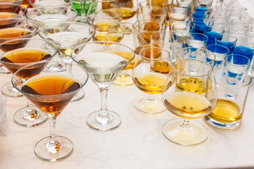 Drinks on a banquet table, shot glasses with blue cocktail, martini glasses, rock glasses, brandy snifters