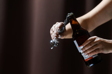 Girl with white nails opens and pours a glass of cider/beer from the bottle.