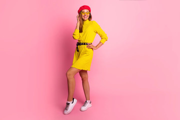 Young smiling woman in acid yellow mini dress is looking to camera at the pink copy space. Full...