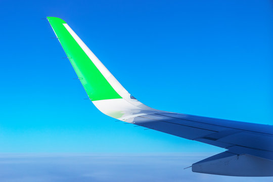 Airplane Wing With Green Stripe. Travel With Eco Friendly Airline. Reducing Carbon Emissions Concept.