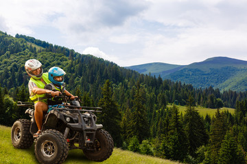 Happy family riding and looking quad bike on mountain. Cute boy on quadricycle. Family summer...