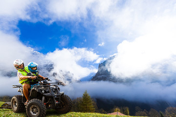 Happy family riding and looking quad bike on mountain. Cute boy on quadricycle. Family summer vacation activity.