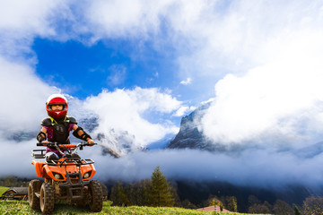 Girl riding quad bike mountain, ATV. Cute child on quadricycle. Kids summer vacation activity.