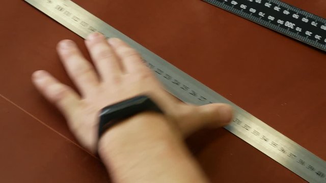 Craftsman makes a line of markings on the leather cloth using a ruler