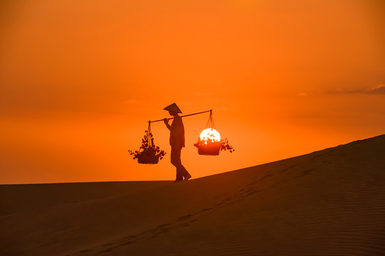 Silhouette of a hawker merchant traveling through the mui ne desert in Vietnam © JKLoma