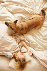 High angle view of young beautiful woman sleeping in bed together with her pet in the bedroom