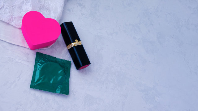 Contraception, medicine, and birth control. Close-up of an oral stimulating drink, a condom, and red lipstick on lace underwear.