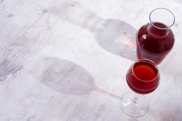 red wine in a wineglass and decanter with shadows isolated on white stone background