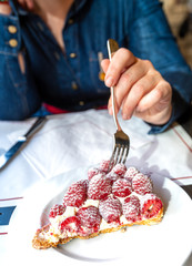 Woman hand holding fork. Traditional danish pastry dessert. Strawberry tart on blue plate.