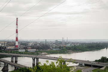 a bridge stretches across the river to an industrial city