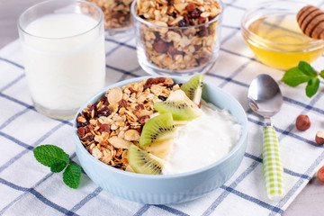 Granola with Greek yogurt kiwi and banana in a bowl with a spoon.