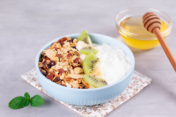 Granola with Greek yogurt kiwi and banana in a bowl with a spoon.