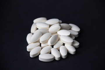 White pills on black background. Free copy space. Medical concept.