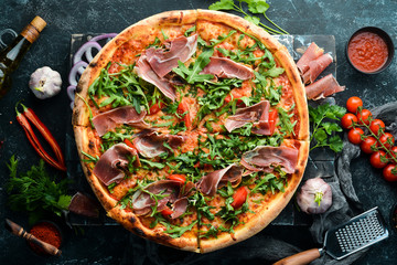 Delicious pizza with prosciutto and arugula. Italian snacks. Top view. Free space for your text.