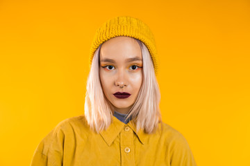 Young woman in total trendy yellow look. Portrait of beautiful punk girl with dark make-up and nose...
