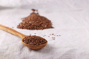 Flax seeds in a wooden spoon on a natural linen tablecloth, Copy space