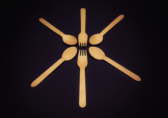 Eco wooden cutlery forks and spoons on a black background close-up.