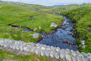 Weide mit einem kleinen Bach bei Oldshoremore an der Küste von Schottland