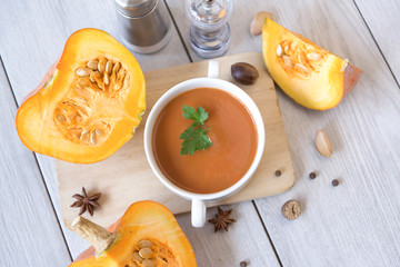umpkin puree soup, pumpkin, spices on a wooden white background.