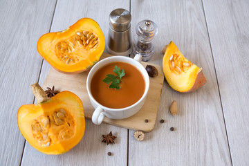 umpkin puree soup, pumpkin, spices on a wooden white background.