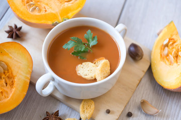 umpkin puree soup, pumpkin, spices on a wooden white background.